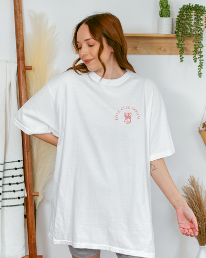 Woman wearing a white oversized t-shirt with red text in a home setting